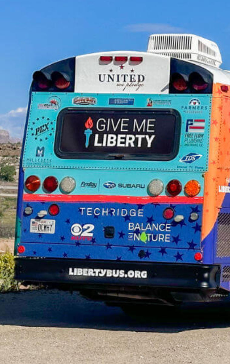 libbus sponsors exterior of united we pledge liberty bus in desert next ro american flag