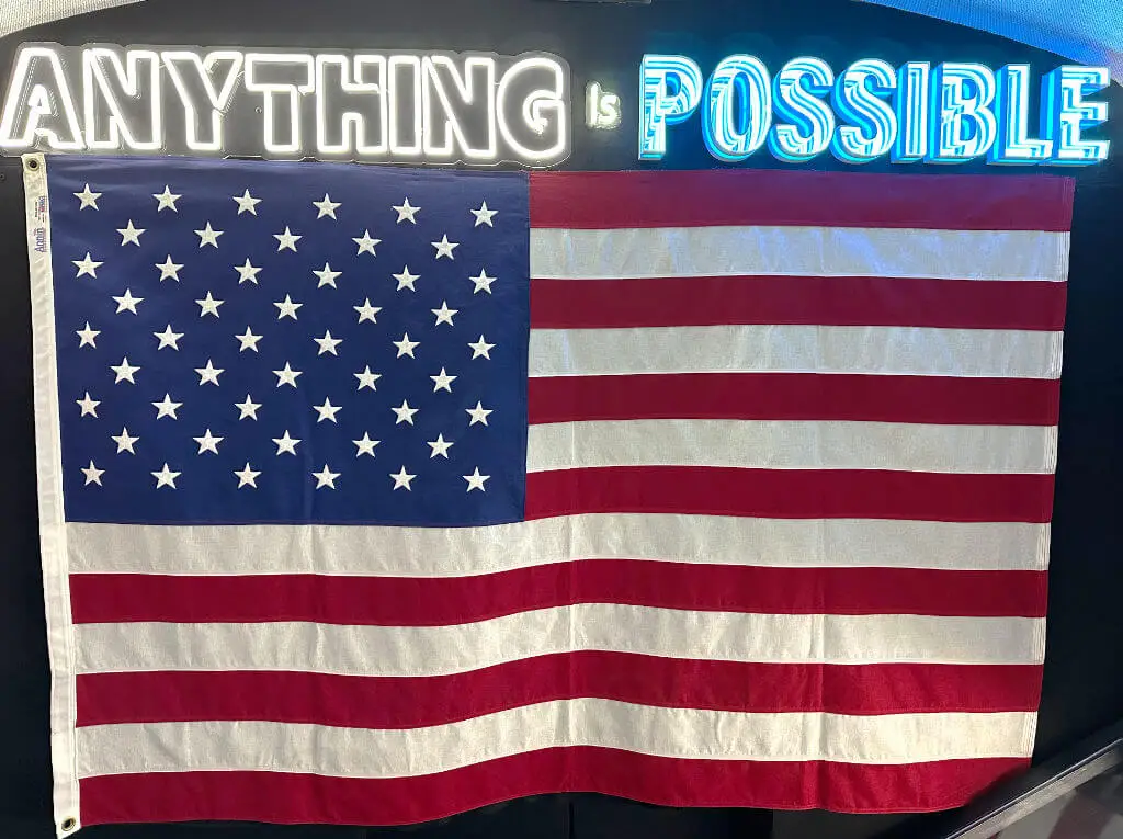 words in neon anything is possible with american flag underneath on wall interior of united we pledge liberty bus