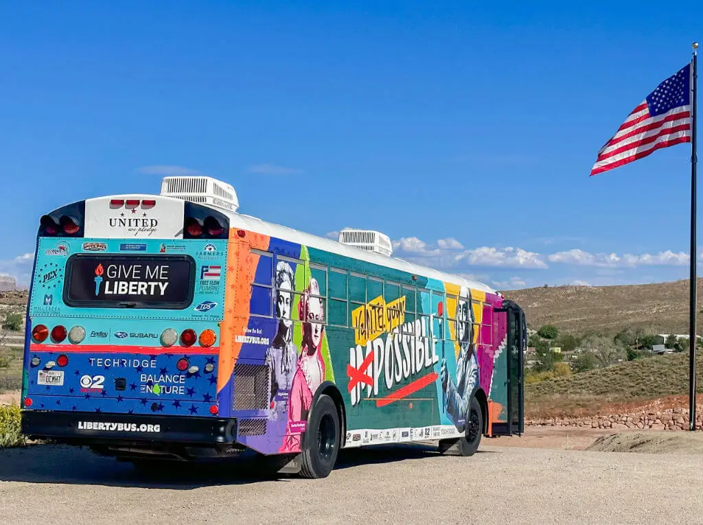 exterior of united we pledge liberty bus in desert next ro american flag