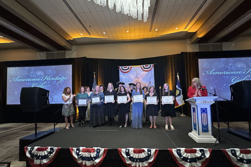 A group of teachers holding certificates on stage at the American Heritage gala teacher appreciation event